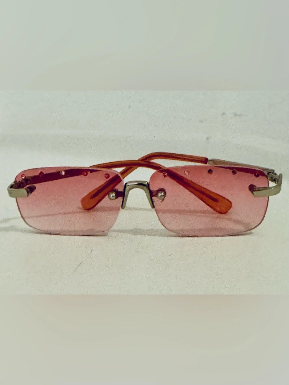 Stylish pink rimless sunglasses adorned with decorative rhinestones. These glass